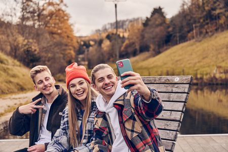 3 Freunde beim Selfie-Shooting auf einer Bank