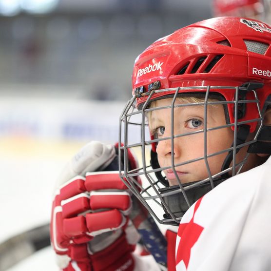 Junge im Eishockeydress mit Helm 