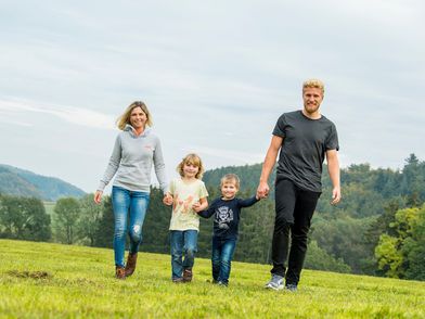 Familie mit zwei Kindern beim Spaziergang auf einer Wiese
