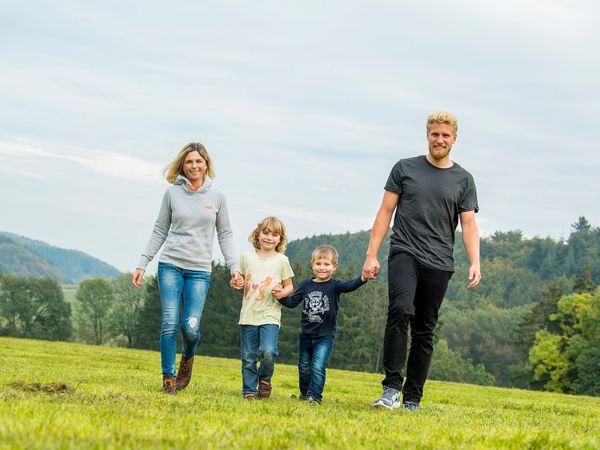 Familie mit zwei Kindern beim Spaziergang auf einer Wiese