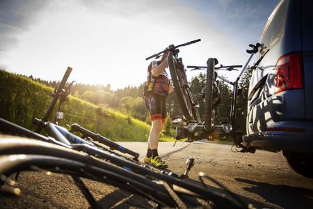 Ein Mann verstaut die Mountainbikes auf dem Fahrradanhänger seines Autos