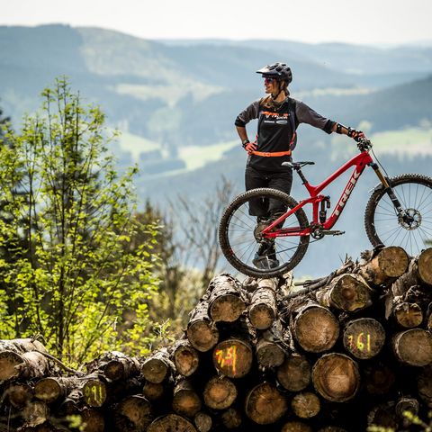 Steffi Marth mit Bike auf Holzstapel vor Landschaftskulisse in der Bikewelt Willingen