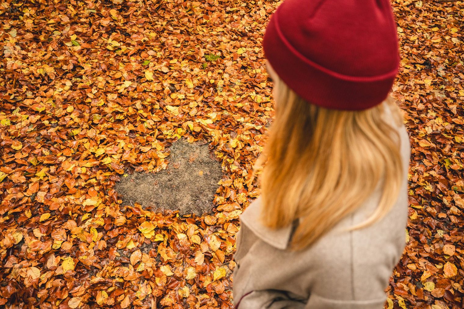Frau neben einem Herz auf laubbedecktem Waldboden