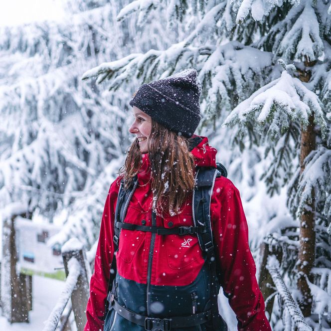 Frau mit Rucksack im verschneiten Winterwald