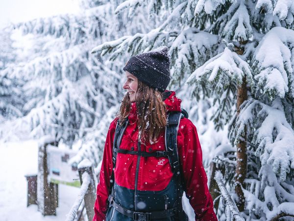 Frau mit Rucksack im verschneiten Winterwald