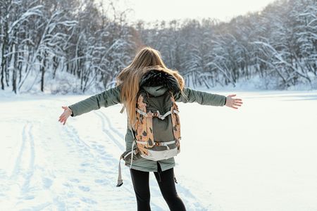 Junge Frau mit Rücksack wandert durch den Schnee