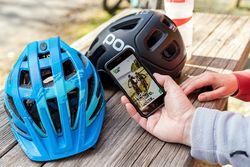 Zwei Fahrradhelme und die Greentrails-App auf dem Smartphone