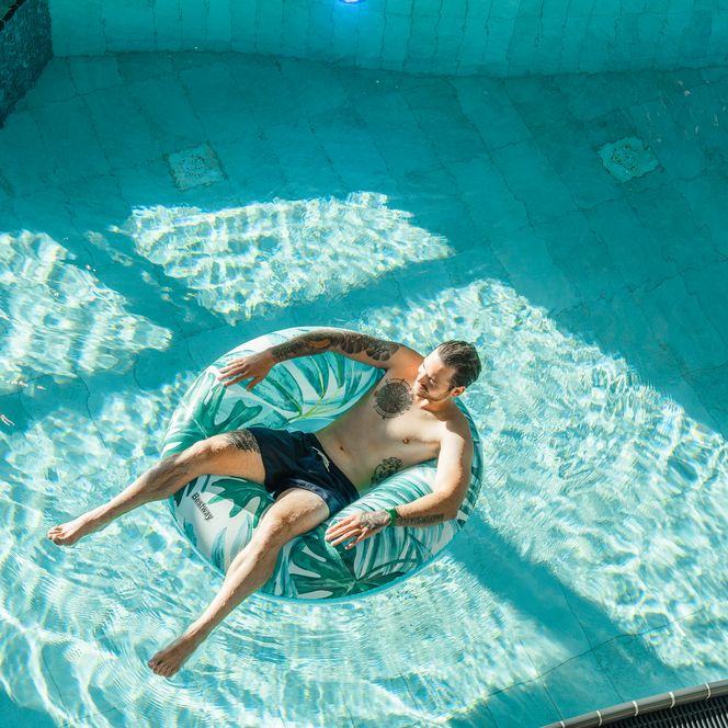 Ein Mann treibt entspannt auf einem Wasserreifen im Laguenbad.