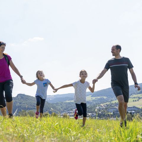 Familie mit zwei Kindern auf einer Wiese, im Hintergrund Willingen